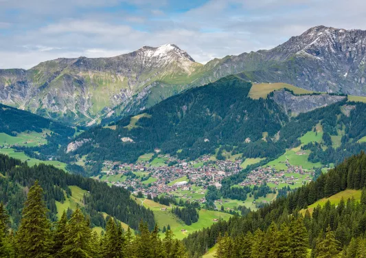 Sky view of a large valley with a town in the center, surrounded by tall mountains
