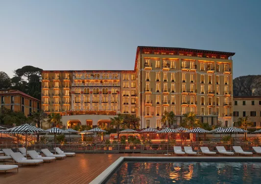 Exterior view of hotel building illuminated with an outdoor pool in front