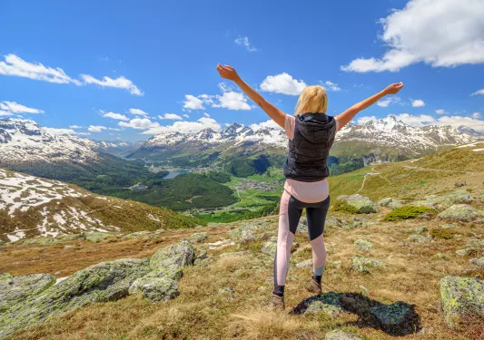 Woman standing on top of a hill with her arms open