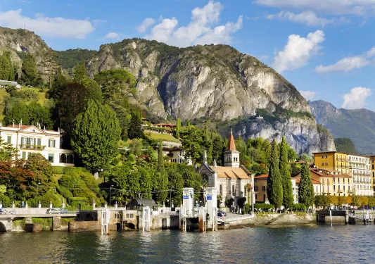 Buildings along a shore dock with large mountains in the background