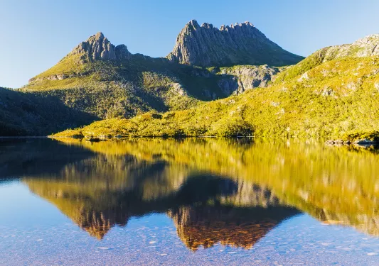 Mountains covered in grass and plants, with a lake in front