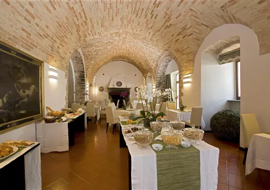 Restaurant dining hall with tables full of bread and food on trays, with large stone ceilings