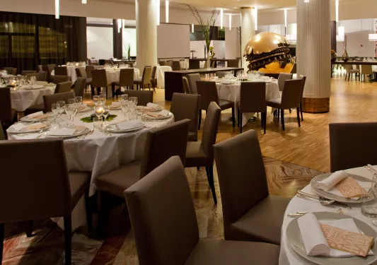 Restaurant with brown, cushioned chairs and white cloths on dining tables