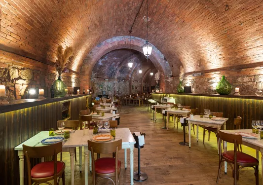 Long tunnel restaurant with brick walls and square dining tables