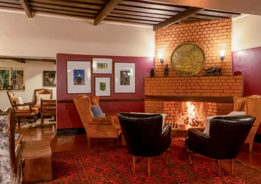 Leather chairs surrounding a brick fireplace, with paintings on the walls