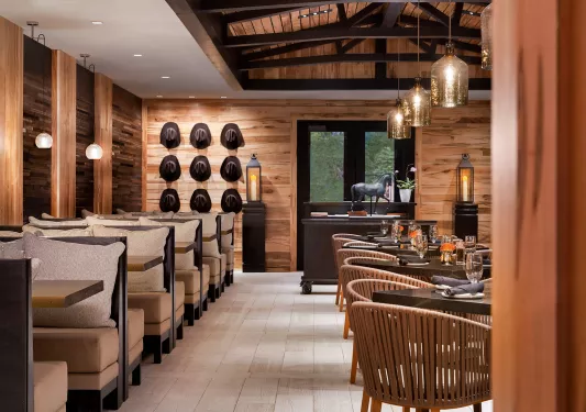 Indoor dining area in a lodge with cowboy hats hanging on the wall