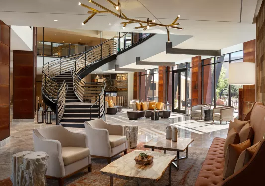 Two-story lobby and seating area with cushioned seats and a staircase in the center