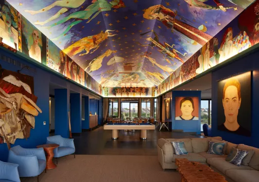 Long, blue room with murals on the ceiling and the walls, with couches along the room