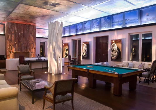 Lounge room with a billiards tables and couches along the room