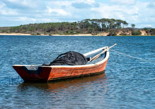 Small, wooden boat with a black tarp in the center