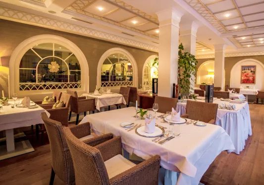 Restaurant dining area with woven chairs and tables with white cloths