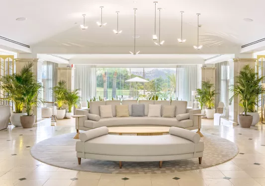 Large room with large, cushioned sofas and large windows in the back