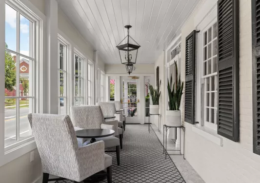 Hallway with potted plants and cushioned, white chairs