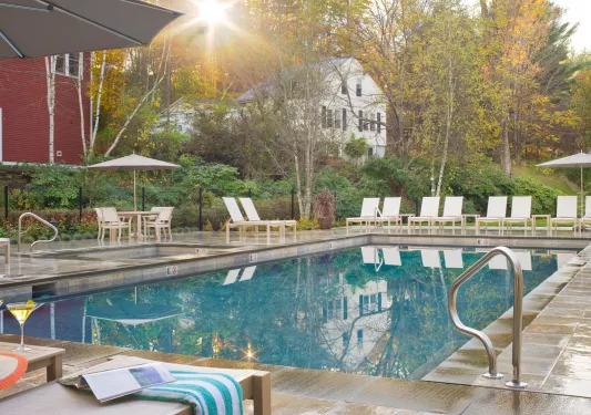 Outdoor pool, surrounded by white chairs and trees in the background