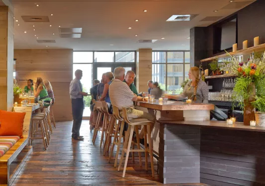 Bar with groups of people sitting at the counter, grabbing drinks from the bartender
