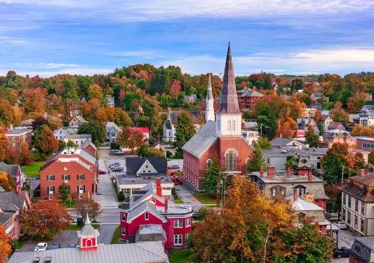 Sky view of a small town with a church building in the center and green and red trees