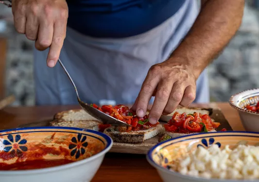 Person adding roasted vegetables to pieces of toast on a plate
