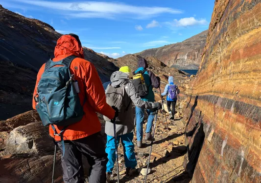 Group of people with hiking poles, walking on gravel trails along a mountain