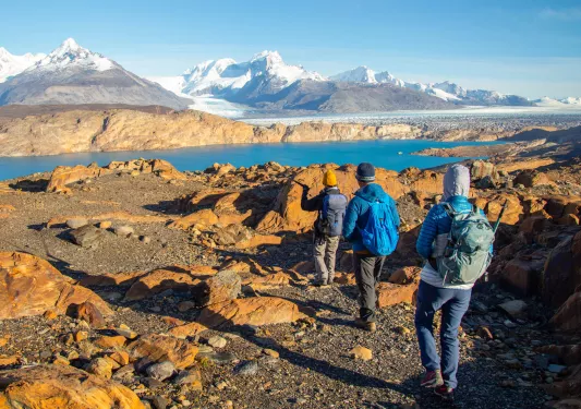 Three people walking on gravel trails towards a lake