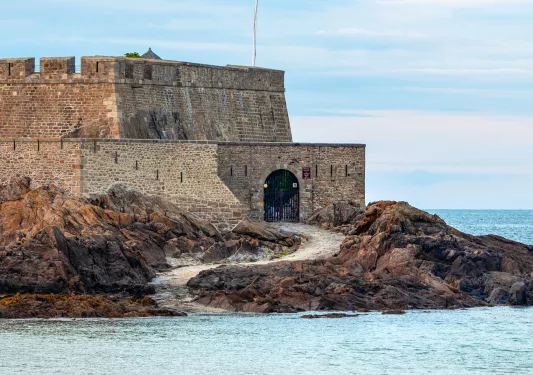 Castle-like stone building with a path leading to the ocean