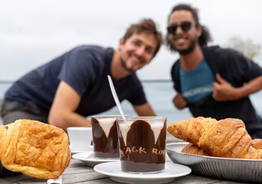 Two people behind a table full of chocolate desserts and croissants