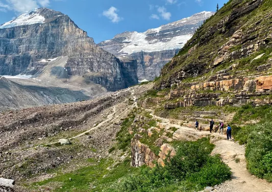 Group of people hiking along a dirt trail with large mountains in the distance