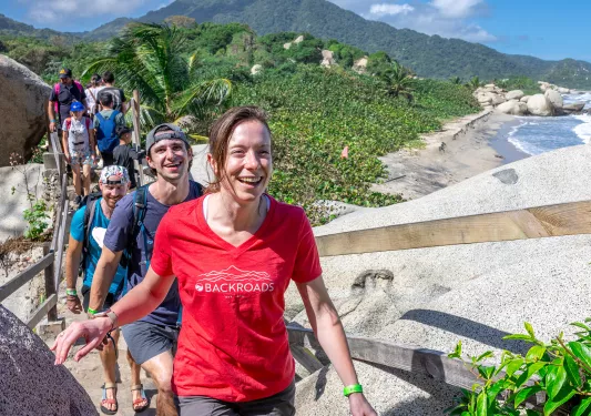 Group of men and women ascending stairs on a hill, with tall trees in the background