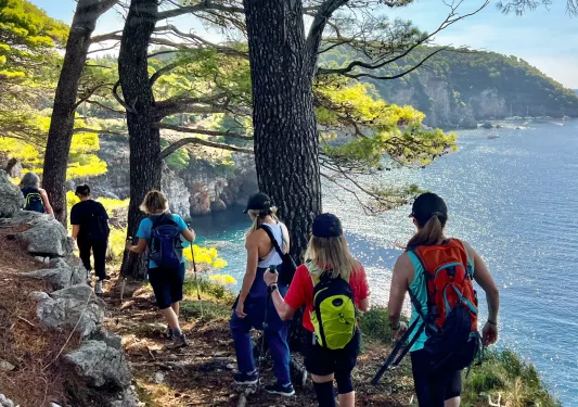 Group of women hiking on a dirt trail by a lake