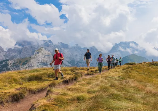 Group of people descending a dirt trail in the middle of a valley