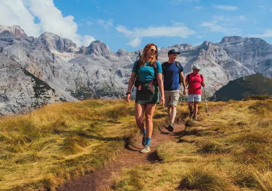 Women and two men hiking on a dirt path on top of a hill