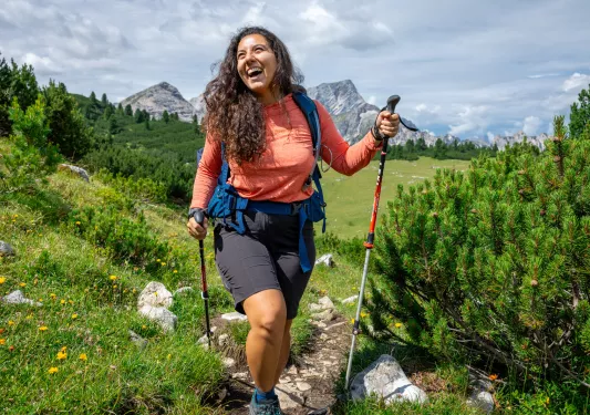 Woman smiling while walking through a grassy trail