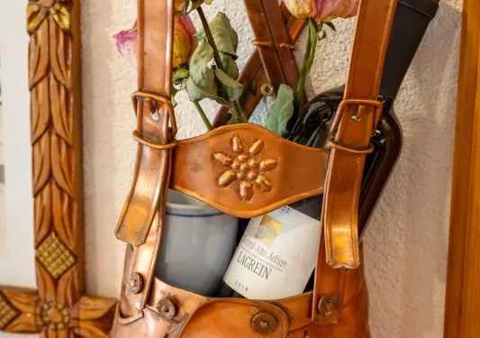 A copper statue of overalls holding a bottle of wine and potted flower