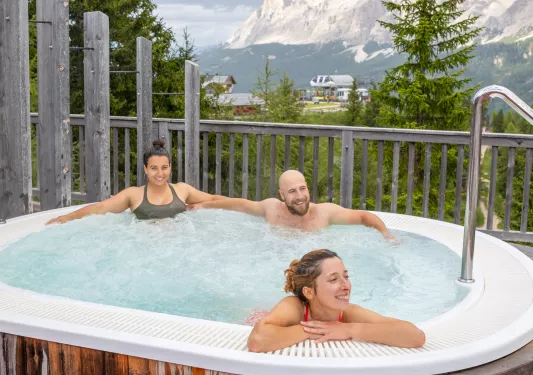 Two women and one man sitting in a hot tub outdoor