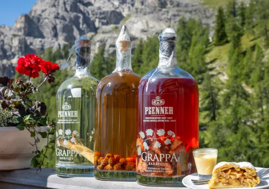 Three large bottles of alcohol on a ledge, with large mountains in the background