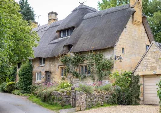 Exterior view of stone building with large bushes and trees surrounding