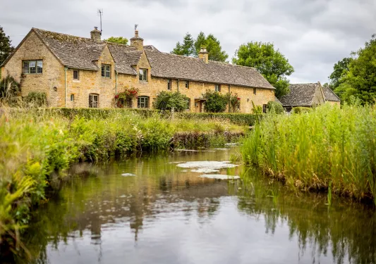 Exterior view of beige brick building with a river in front