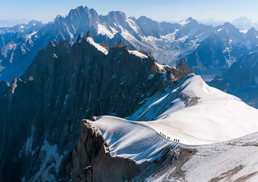 Top view of snowcapped mountains with larger mountains in the distance