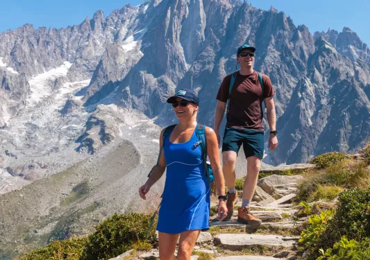 Man and woman descending a path of rocks on top of a mountain