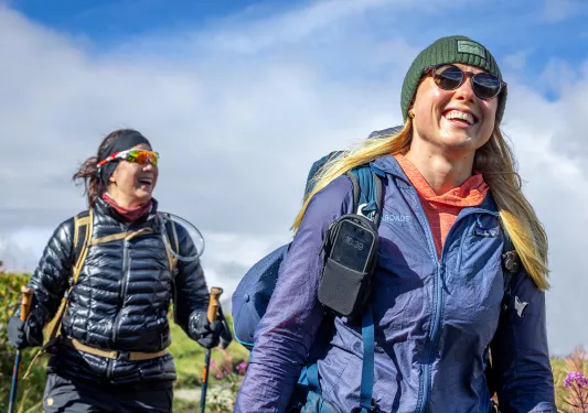 Two women smiling while hikings in an open field