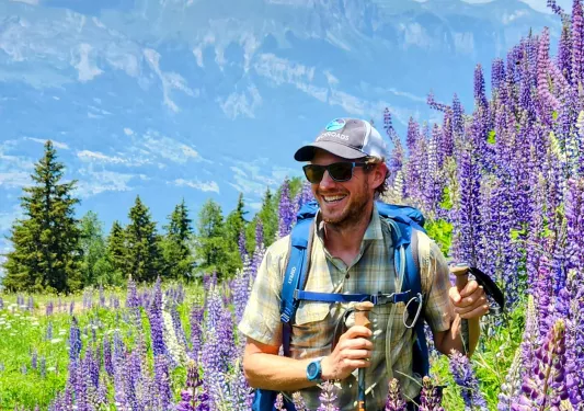 Man hiking with tall lavender flowers to the right