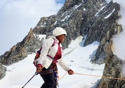 Woman in snow gear hiking on a snowy trail with a mountain in the background