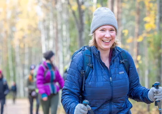 Woman smiling while trekking with walking poles