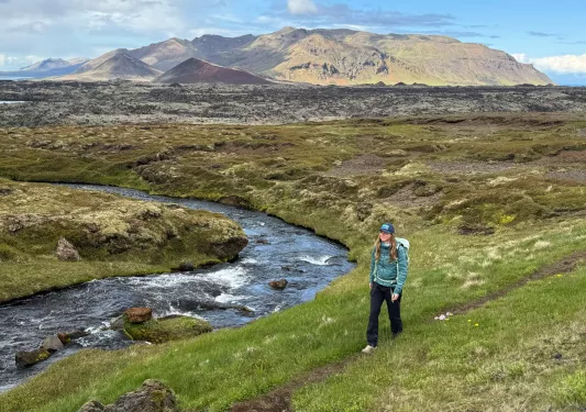 Woman on a hill, hiking with a river in the background