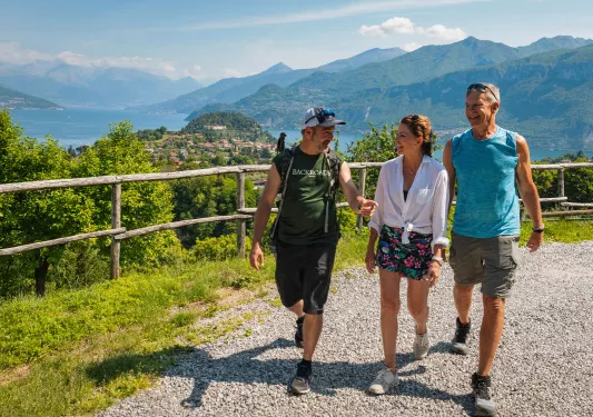 Woman and 2 men walking a gravel path with a town in the distance