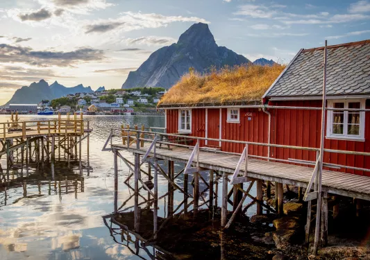 Red building in front of a large lake, with mountains in the distance