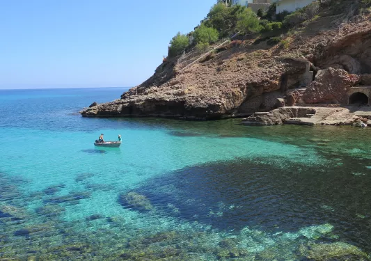 Two people on a small boat on the coast of the ocean