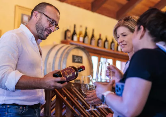 Man pouring wine into the glasses of two women