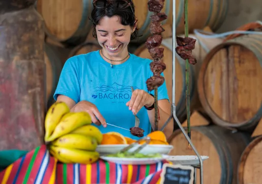 Woman smiling while grabbing meat from a large, metal skewer