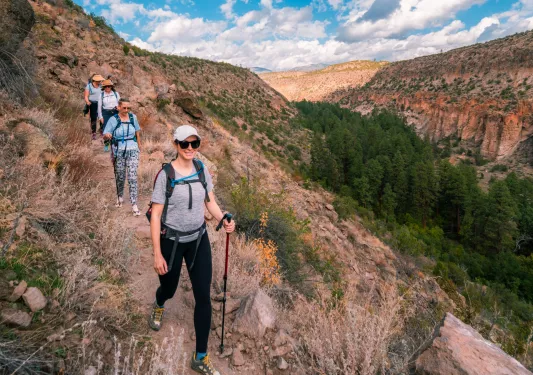 Group of women with walking poles descending a dirt trail