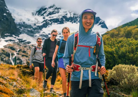 Two men and women hiking on a trail with foggy mountains in the background